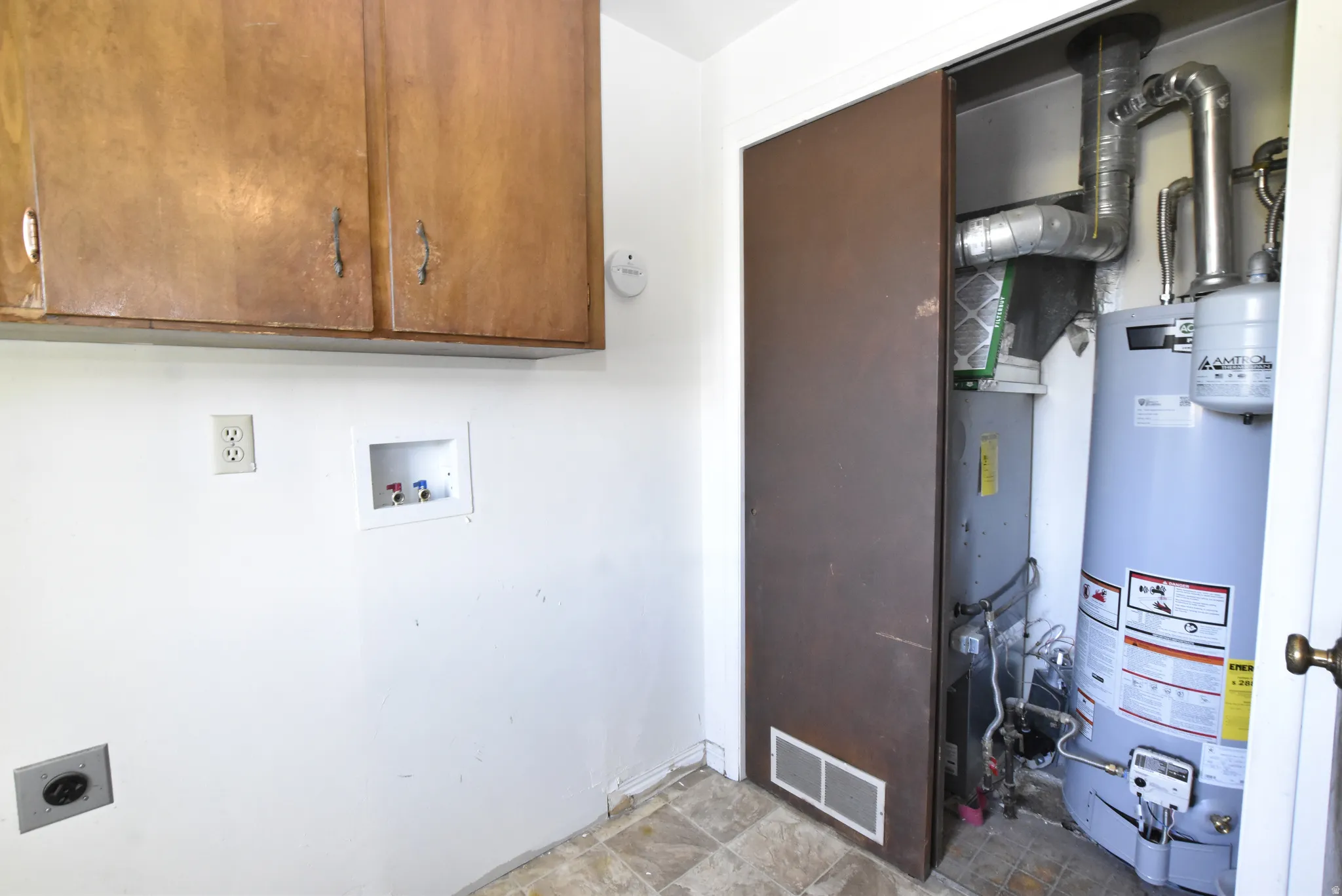 Dedicated utility area featuring a water heater, furnace, and wall-mounted wooden cabinetry for storage