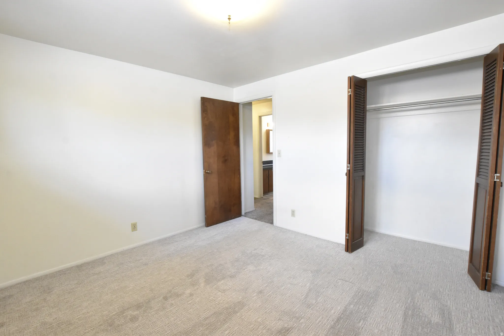 Bedroom featuring light-toned carpeting, white walls, and a ceiling-mounted light fixture