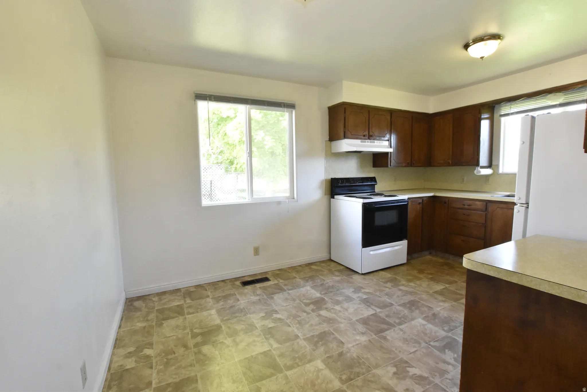 Kitchen featuring wood cabinetry, laminate countertops, and resilient flooring