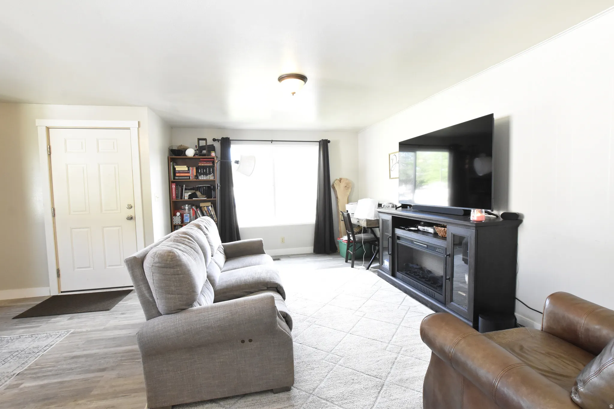 Living area featuring wood-finish flooring, a bright window, and a built-in media console with an electric fireplace