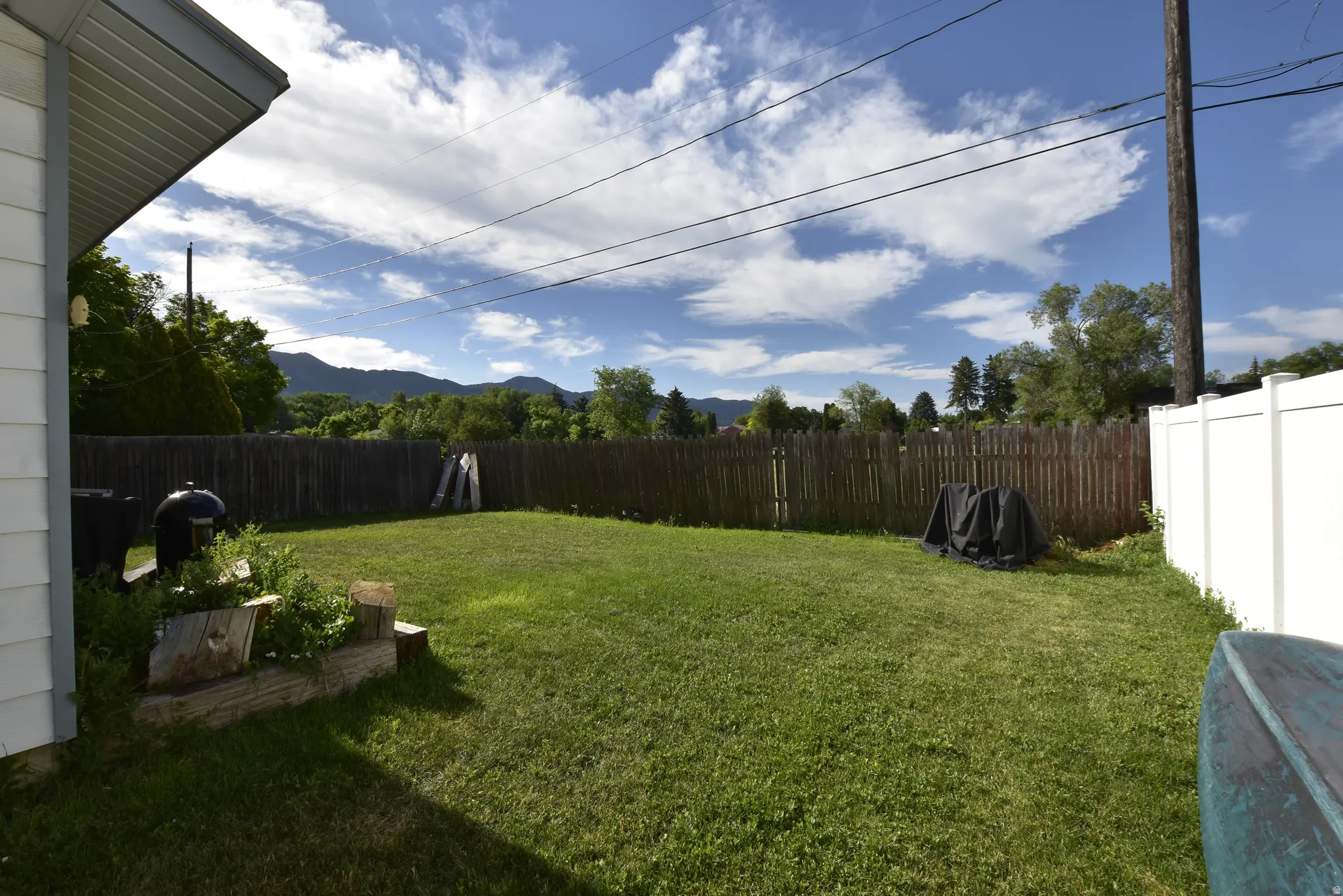 Expansive grassy backyard featuring wood fencing and a white vinyl privacy fence
