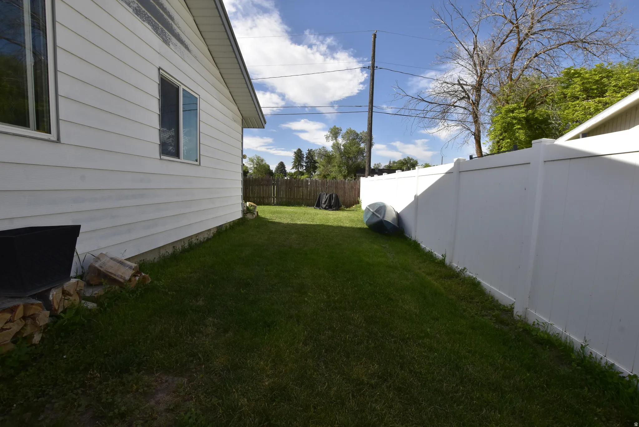 Expansive grass yard with a white vinyl fence and white siding