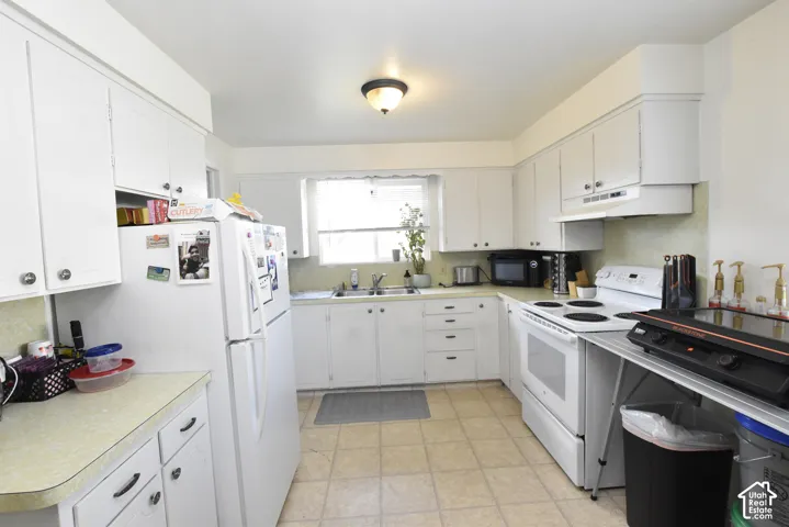 Kitchen featuring white cabinetry, light-toned countertops, a window over the sink, and tile flooring