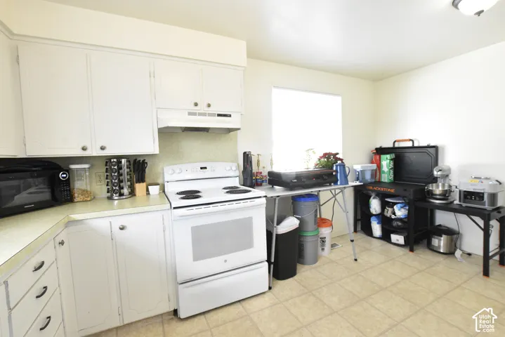 Kitchen featuring white cabinetry with brushed nickel hardware, white range, and a window providing natural light
