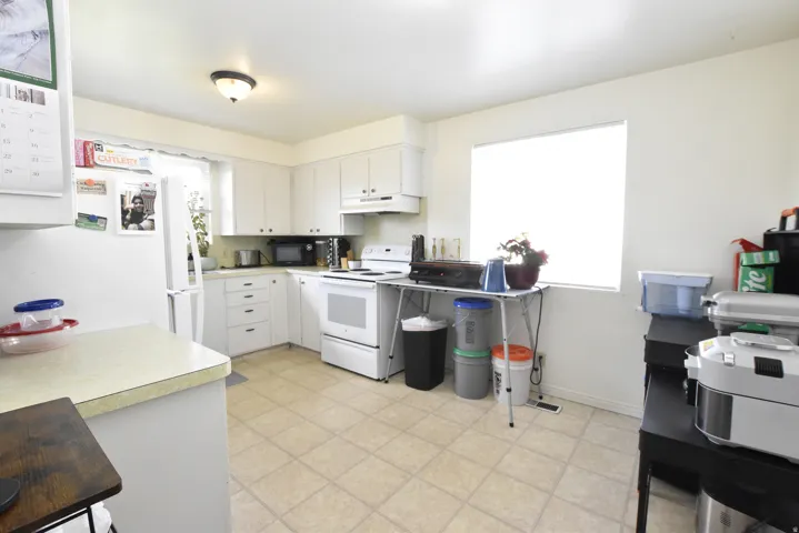 Kitchen featuring white cabinetry, light-toned countertops, and a window