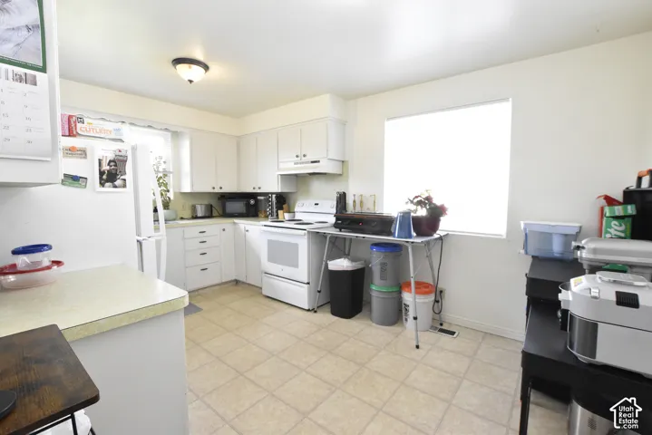 Kitchen featuring white cabinetry, light-toned countertops, and a window