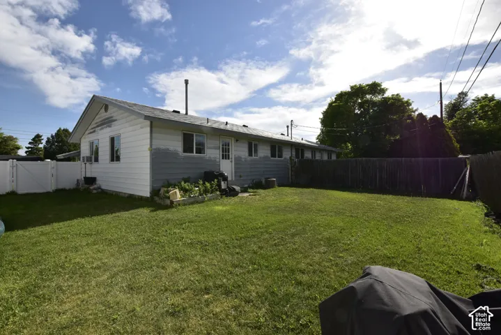Expansive backyard featuring a manicured lawn, a full privacy fence, and a white vinyl fence section