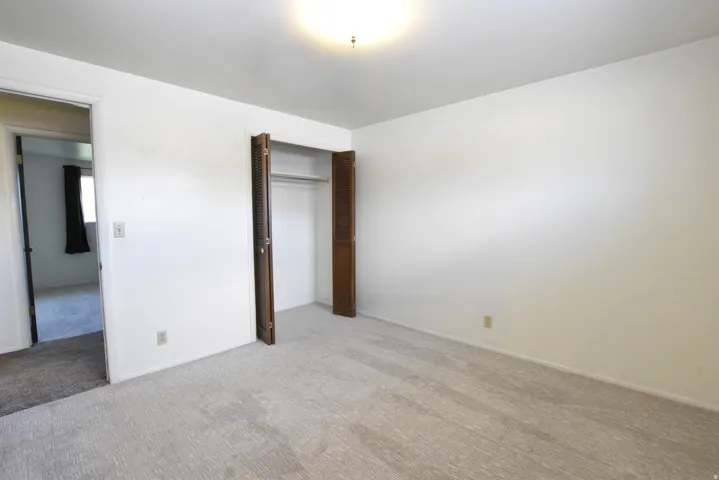 Carpeted room featuring a built-in closet with bi-fold louvered doors