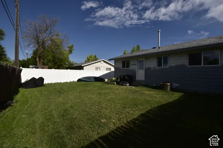 Expansive green lawn with a white privacy fence