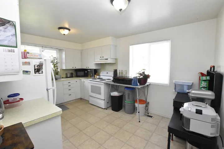 Well-lit kitchen featuring white cabinetry, a white electric range, and a white refrigerator
