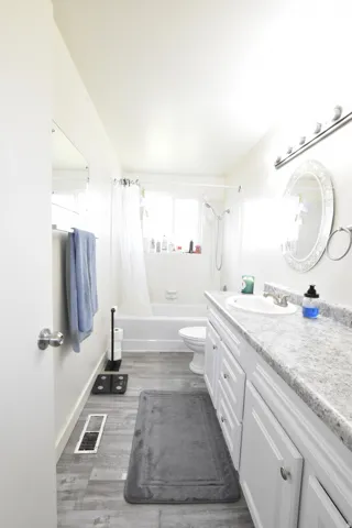 Bathroom featuring a white vanity with dual sinks, a speckled countertop, and white cabinetry