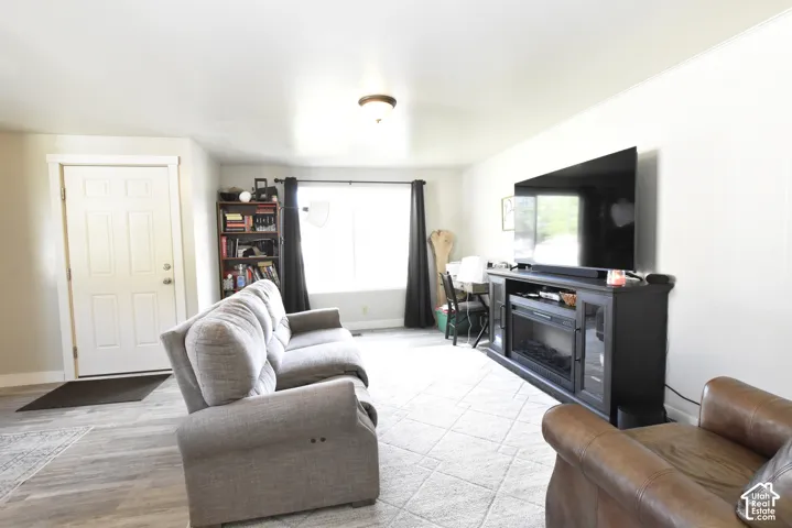 Living area featuring wood-finish flooring, a bright window, and a built-in media console with an electric fireplace