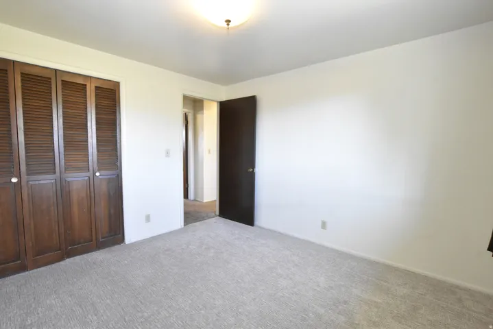 Interior room featuring light-colored wall paint and a textured carpet flooring