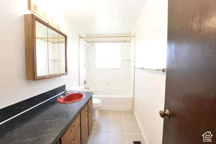 Bathroom featuring a lengthy vanity with a dark countertop and red basin sink