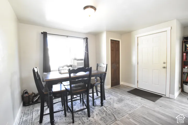 Dining area featuring a large window, light gray walls, wood-finish flooring, and a white paneled entry door