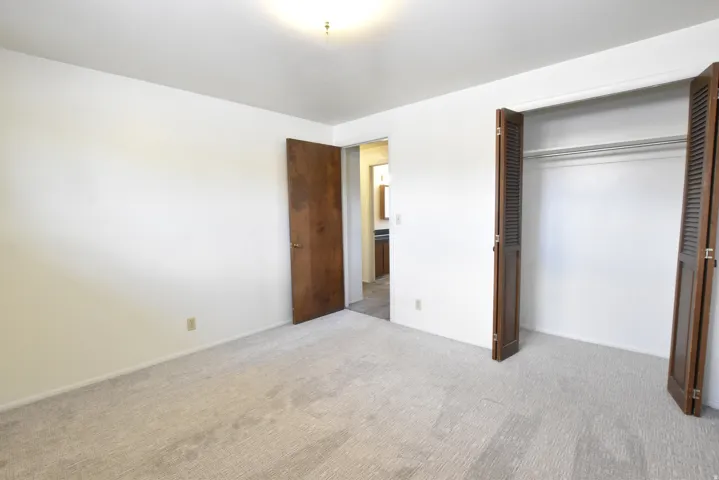 Bedroom featuring light-toned carpeting, white walls, and a ceiling-mounted light fixture