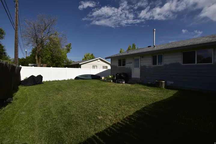 Expansive green lawn with a white privacy fence