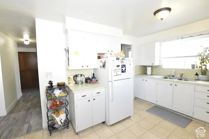 Kitchen featuring white cabinetry, a double basin stainless steel sink, a window over the sink, and tile flooring