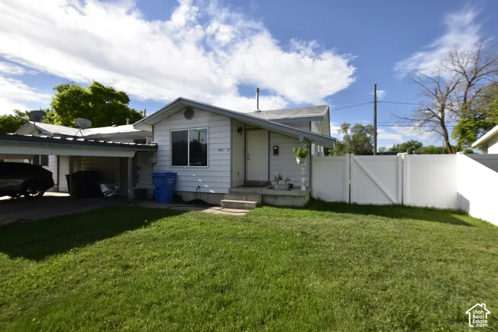 Single-story residence featuring white siding, a covered carport, and a white privacy fence