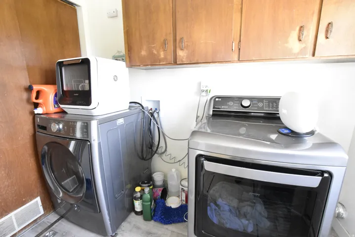 Dedicated laundry area featuring overhead wood cabinetry and light gray flooring