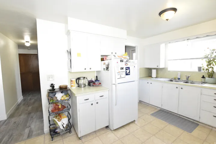 Kitchen featuring white cabinetry, a double basin stainless steel sink, a window over the sink, and tile flooring