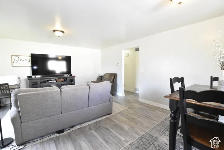Open-concept living space featuring wood-finish flooring, recessed lighting, and crisp white walls