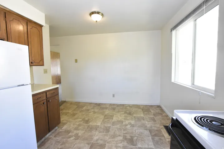 Kitchen space featuring a window, patterned floor tile, white walls, and a ceiling-mounted light fixture