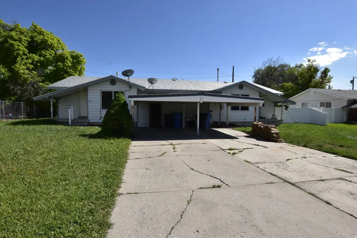 Ranch-style exterior featuring a covered carport, concrete driveway, and front lawn