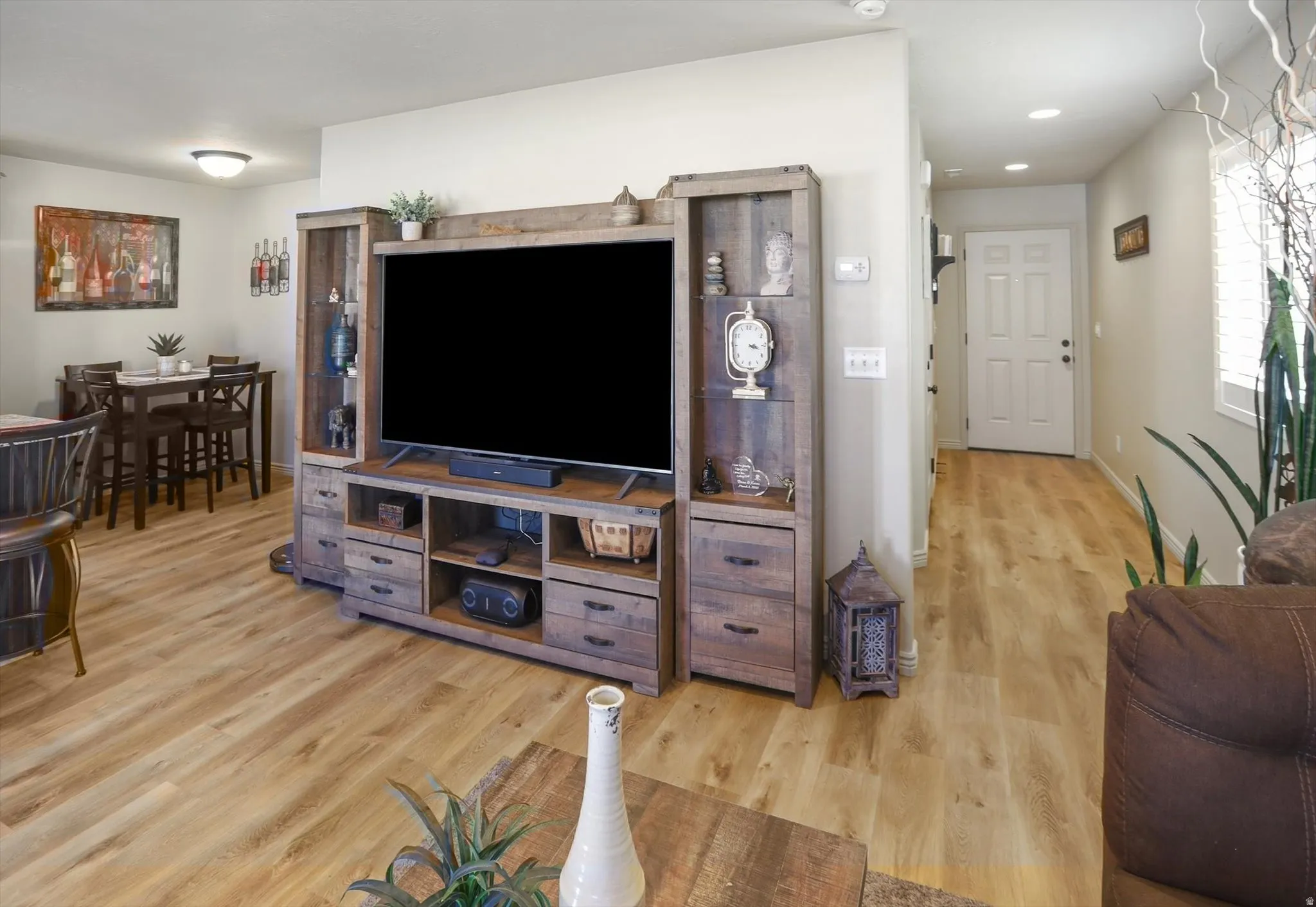 Open-concept living space featuring wood-finish flooring, recessed lighting, and a white six-panel entry door