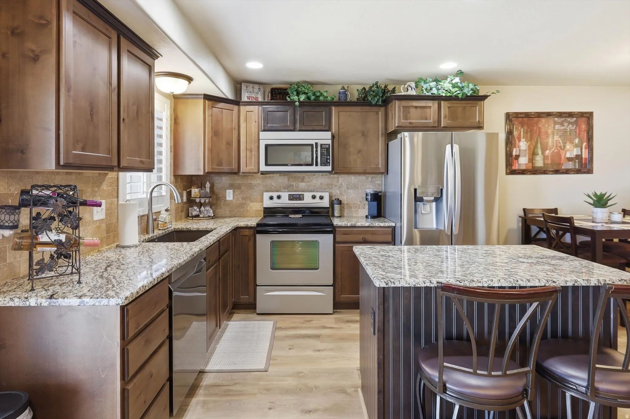 Kitchen featuring wood-finish cabinetry, light-toned granite countertops, and stainless steel appliances