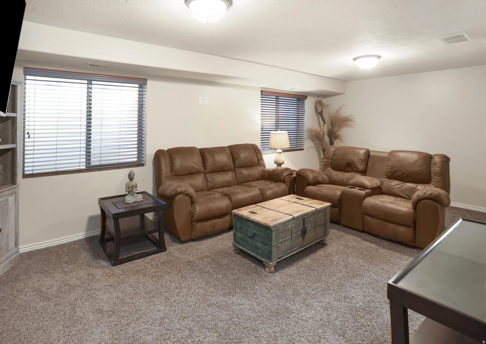 Carpeted living space featuring recessed lighting and two windows with blinds
