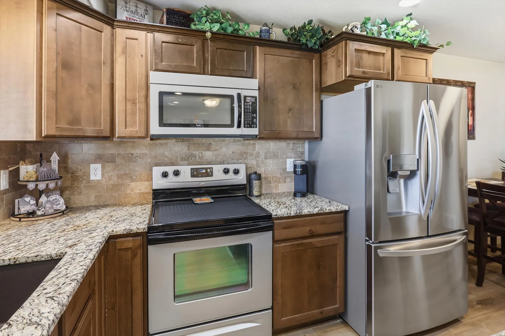 Kitchen featuring wood cabinetry, a stainless steel French door refrigerator, a stainless steel range with a flat cooktop, a built-in microwave, and granite countertops
