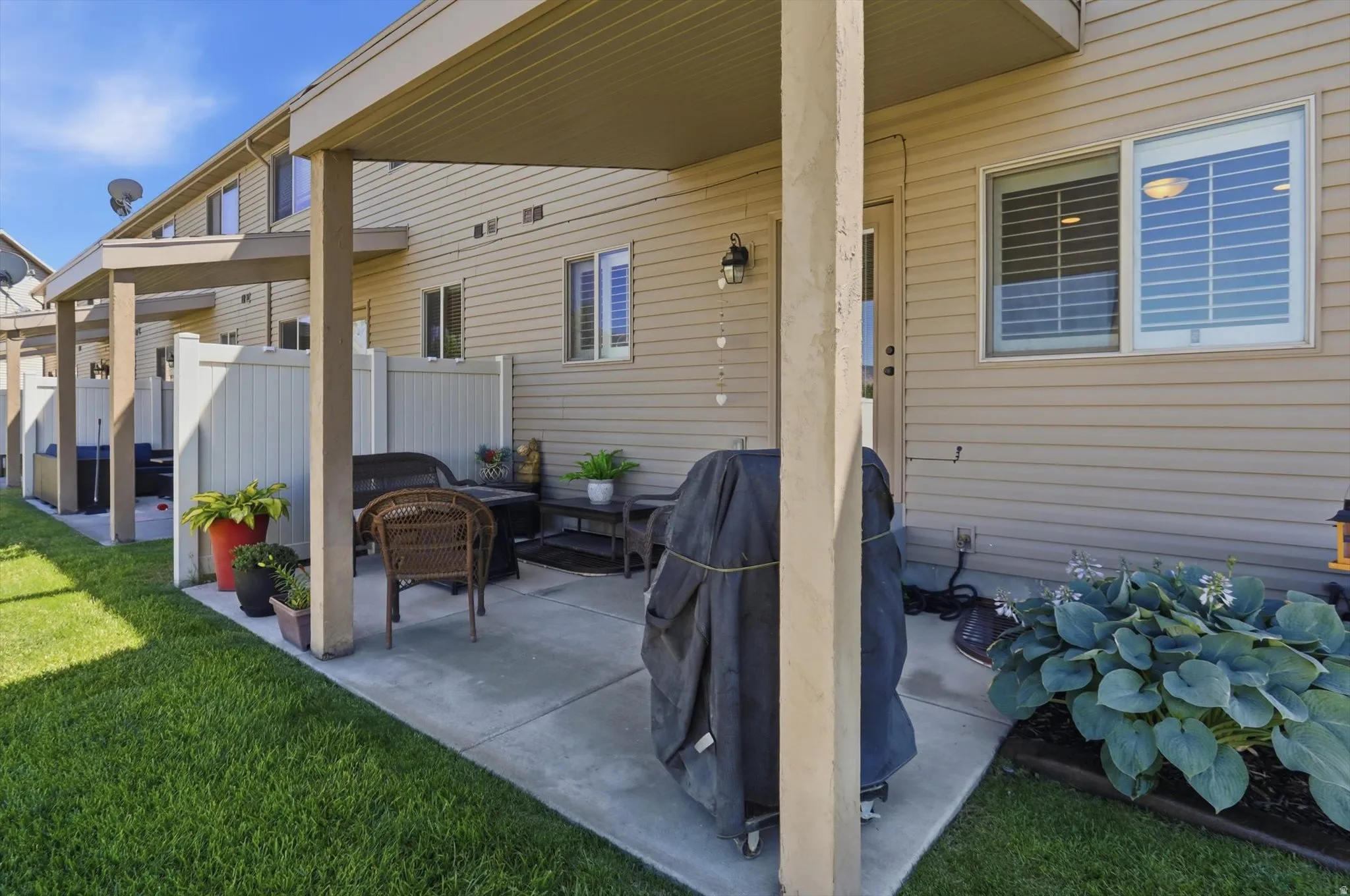 Covered patio with concrete surface, vertical privacy fencing, and exterior wall lighting