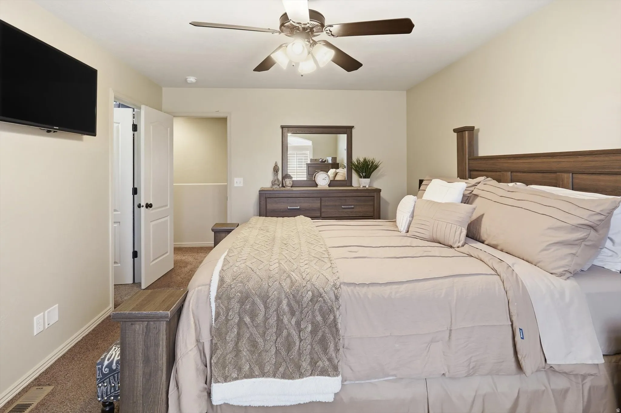 Carpeted bedroom featuring a ceiling fan with integrated lighting, a wall-mounted television, and a built-in closet with shelving