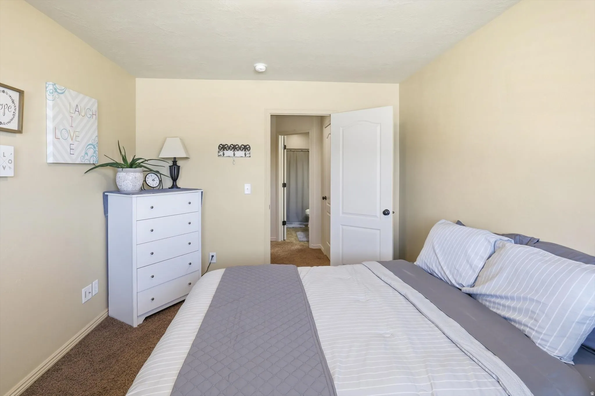 Carpeted room featuring a white interior door with dark hardware, leading to an additional space