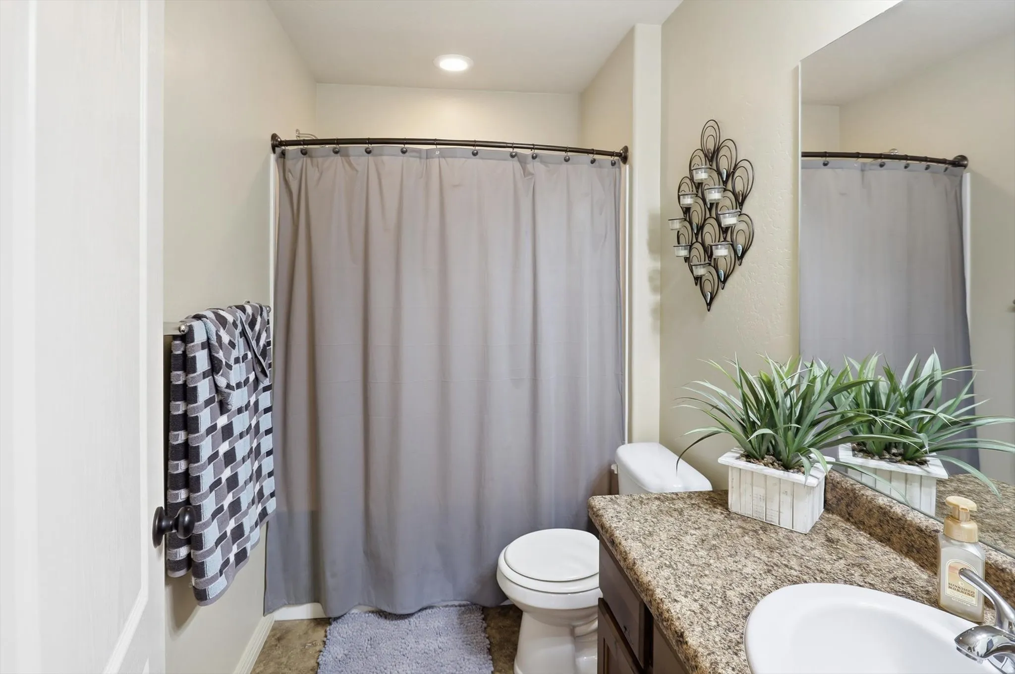 Bathroom vanity featuring a speckled countertop, undermount sink, and a large wall-mounted mirror