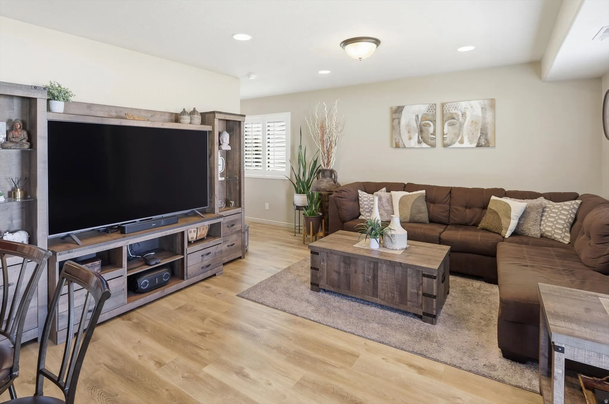 Spacious room featuring wood-finish flooring, recessed lighting, and a large window with plantation shutters
