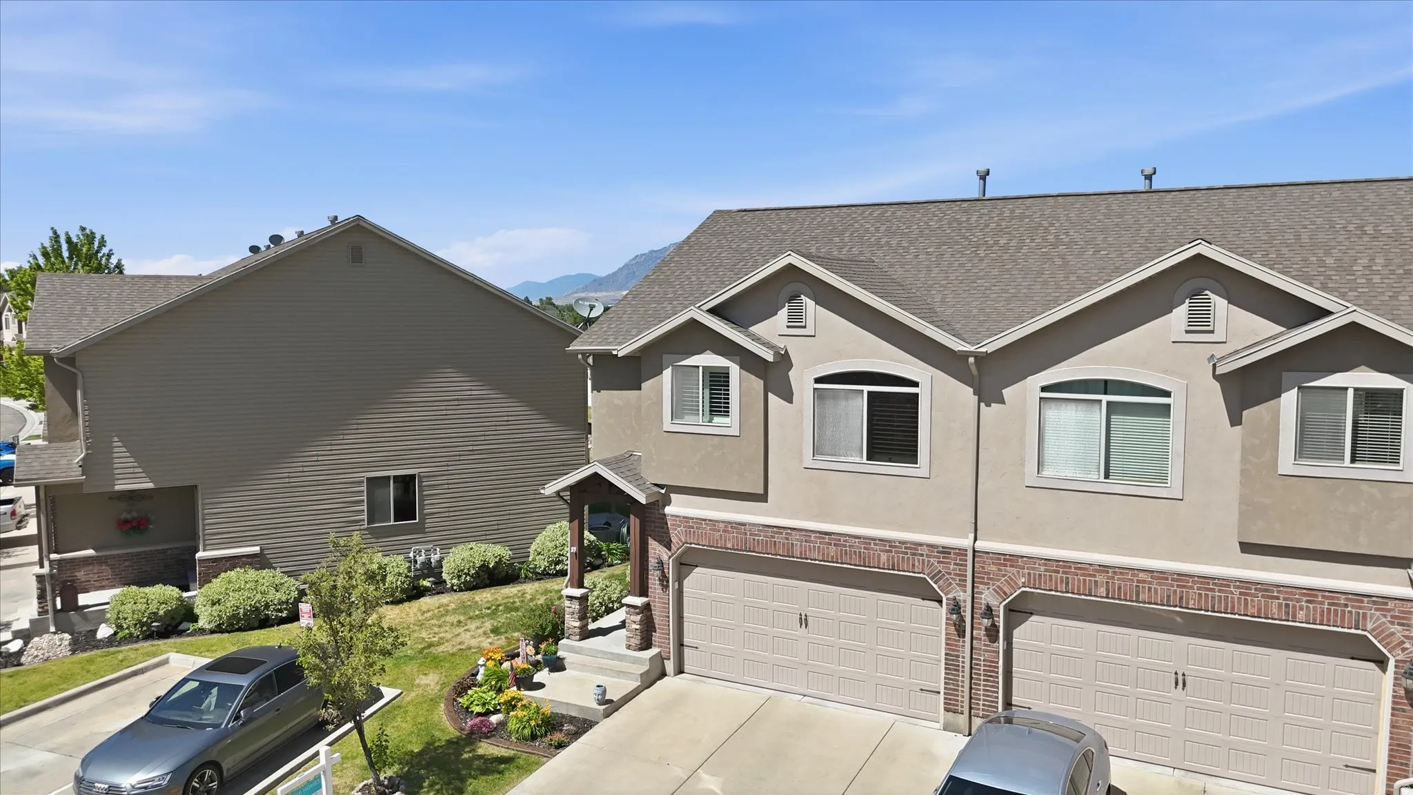 Townhome exterior featuring a two-car garage, stone and brick facade accents, and a covered entryway