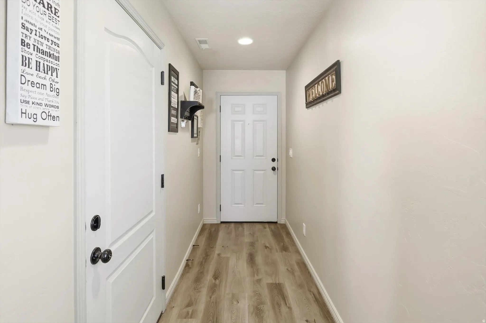 Hallway entry featuring wood-finish flooring, light-toned walls, and recessed lighting