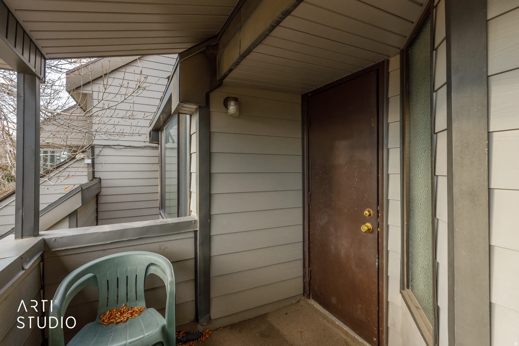 Covered entry porch featuring a solid brown entry door with brass hardware and a textured glass sidelight