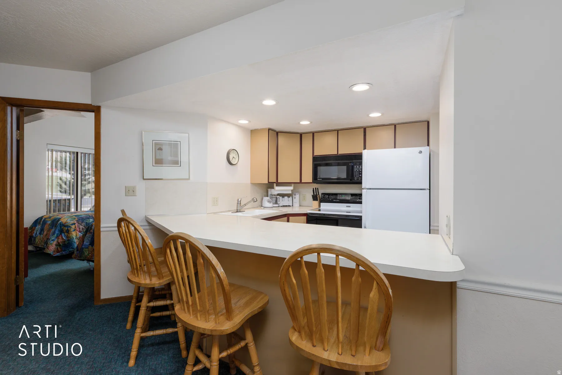 Kitchen featuring a breakfast bar with seating, wood-finish cabinetry, white appliances, and a white countertop