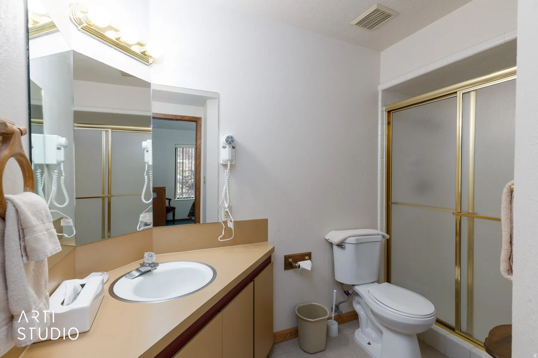 Bathroom featuring a vanity with a drop-in sink and laminate countertop, an integrated mirror, and a gold-framed shower with frosted glass doors
