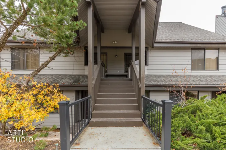 Covered entryway with painted wood steps and dark metal railings