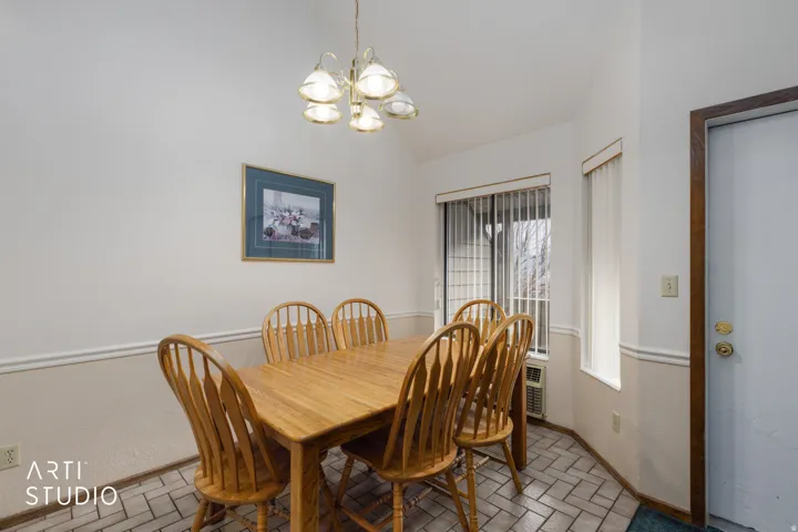 Dining area featuring a vaulted ceiling, patterned tile flooring, and wainscoting