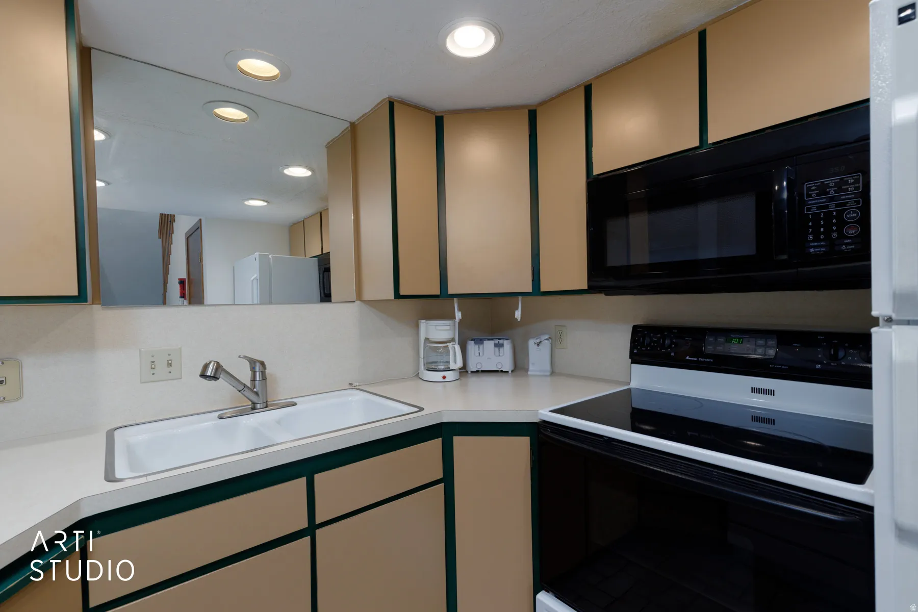 Kitchen featuring light-toned cabinetry with green trim, a built-in over-the-range microwave, and a smooth-top electric range