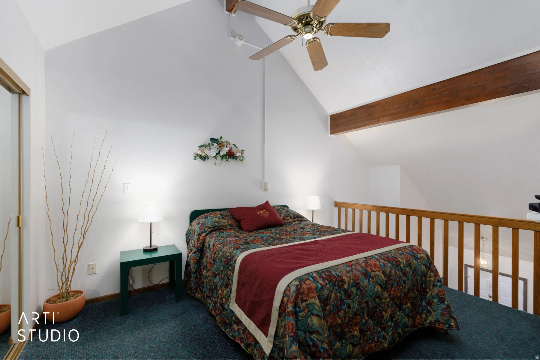Vaulted ceiling loft bedroom featuring a ceiling fan, exposed wood beam, wood-finish railing, and wall-to-wall carpeting