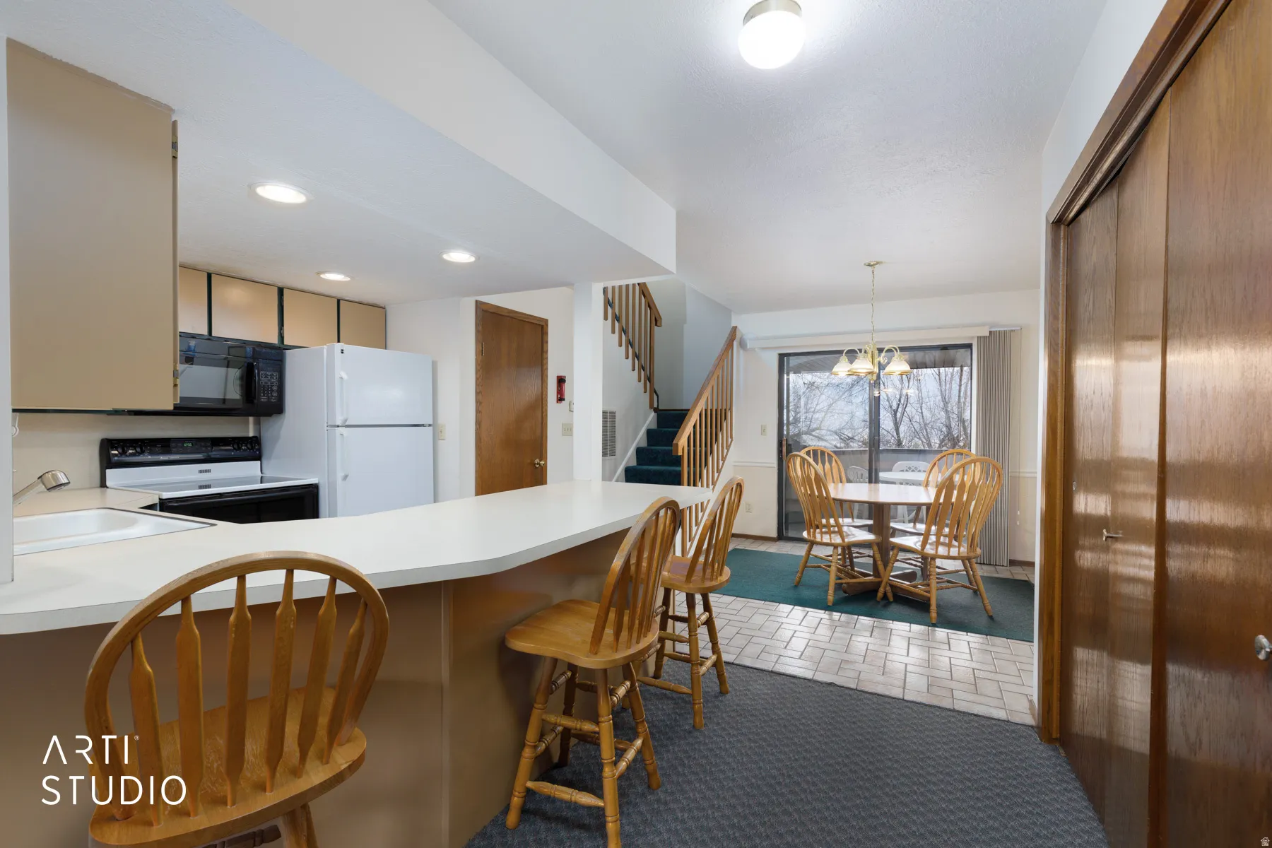 Kitchen with a breakfast bar, recessed lighting, white appliances, and wood-finish cabinetry