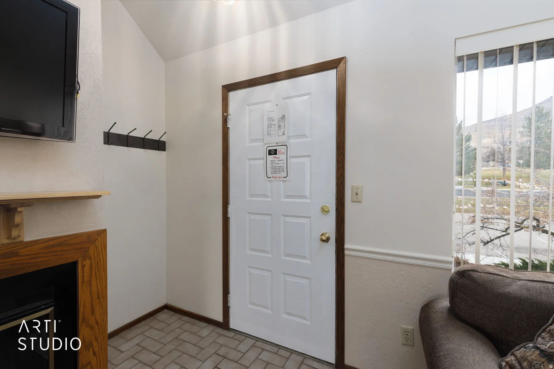 Entryway featuring a paneled door with wood-finish trim, herringbone tile flooring, and a window with vertical blinds