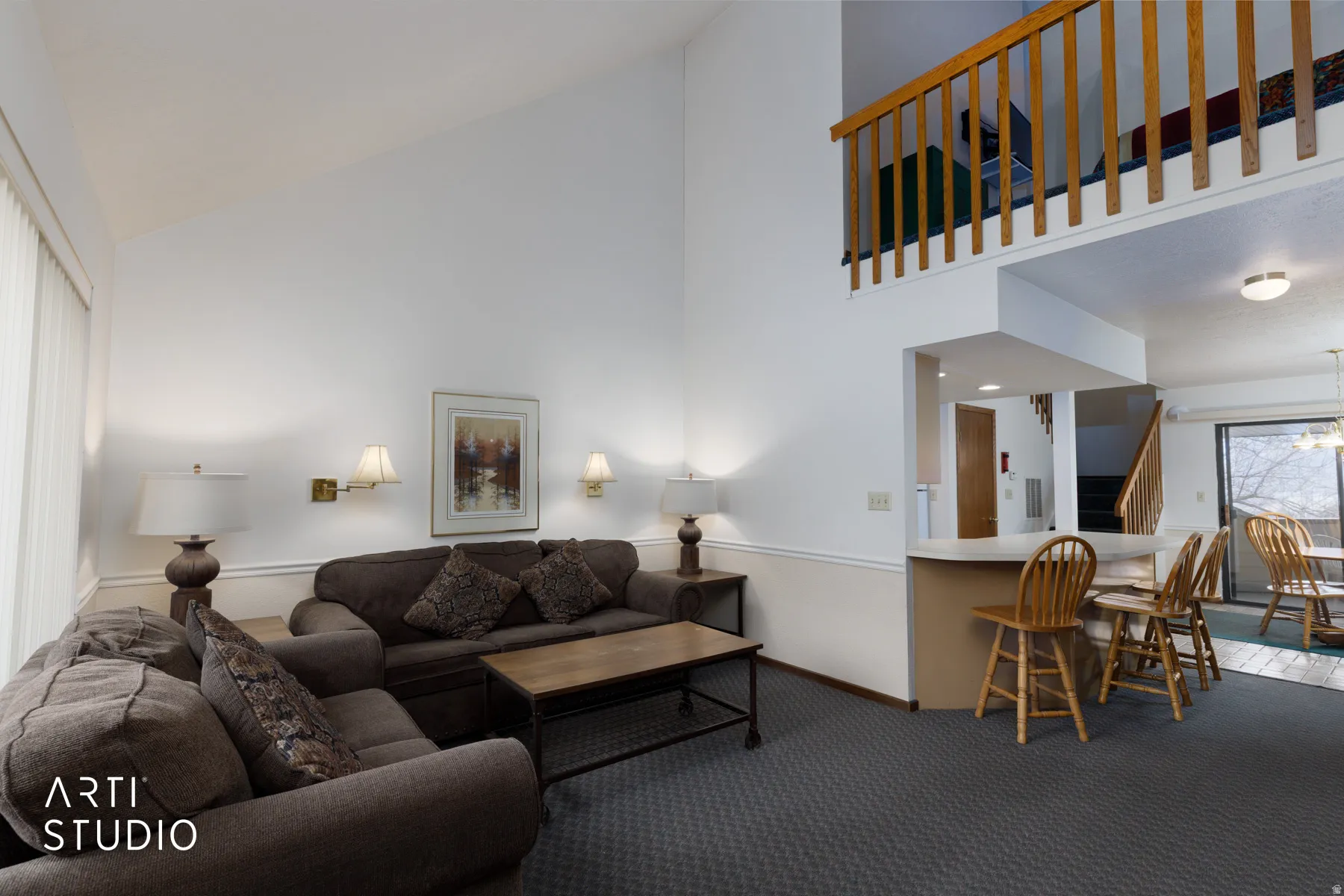 Vaulted ceiling living area featuring a wood railing loft, neutral wall paint, and wall sconce lighting