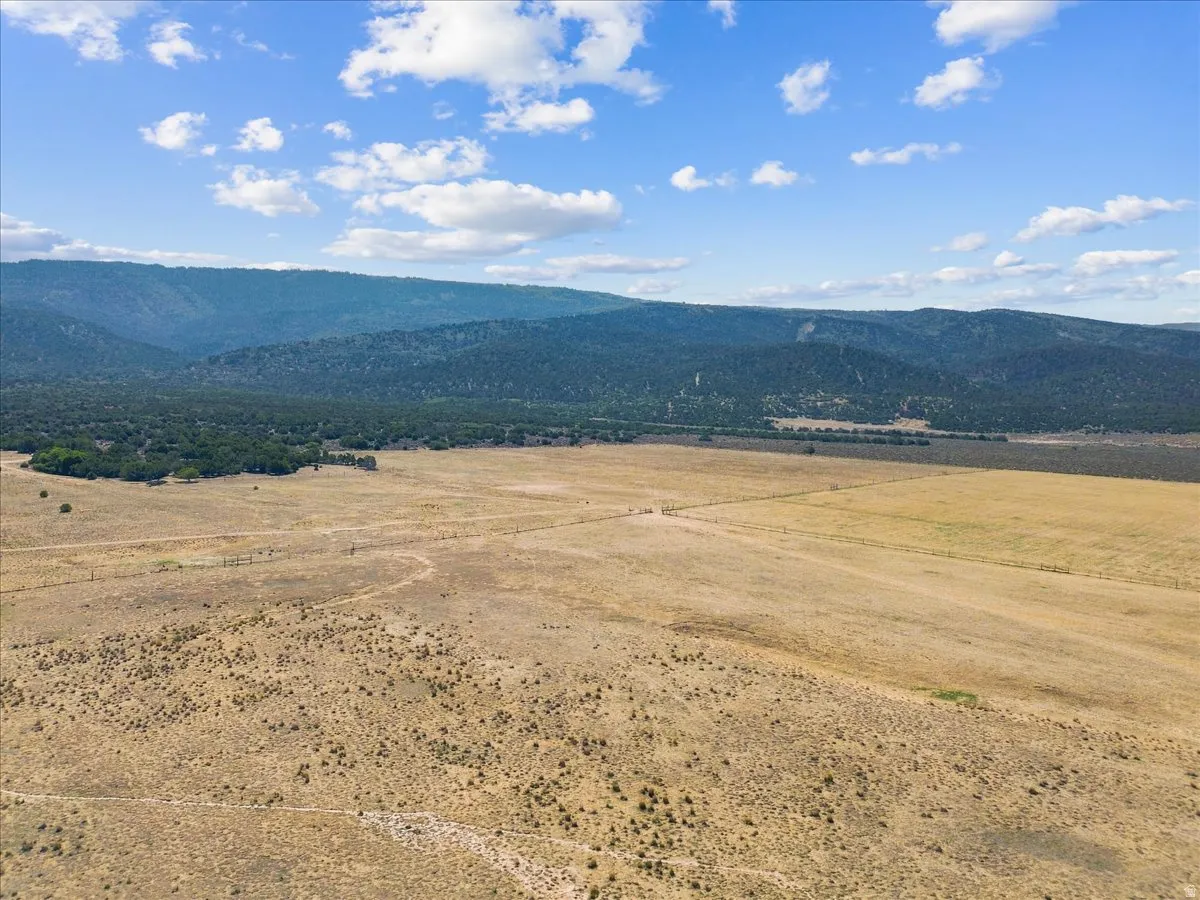 Expansive natural landscape with a mountainous backdrop, featuring open fields and distant treelines
